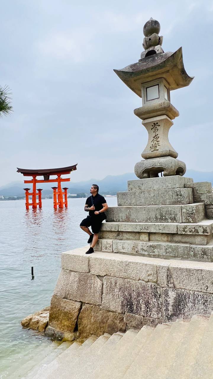 A person posing near the iconic torii gate of Itsukushima Shrine.