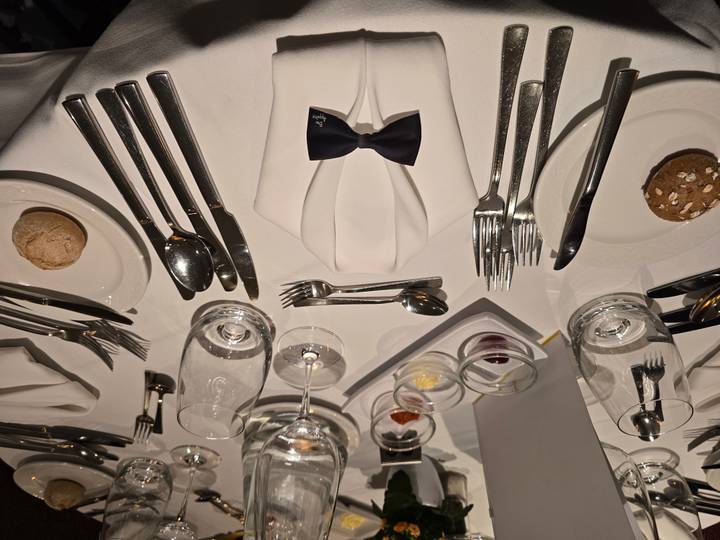 Formal table setting with fine dining cutlery and glassware.