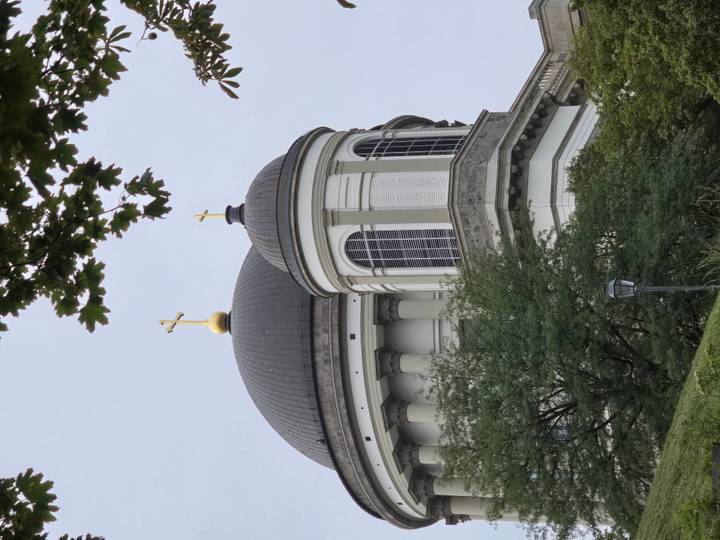Dome and cross architecture behind trees.