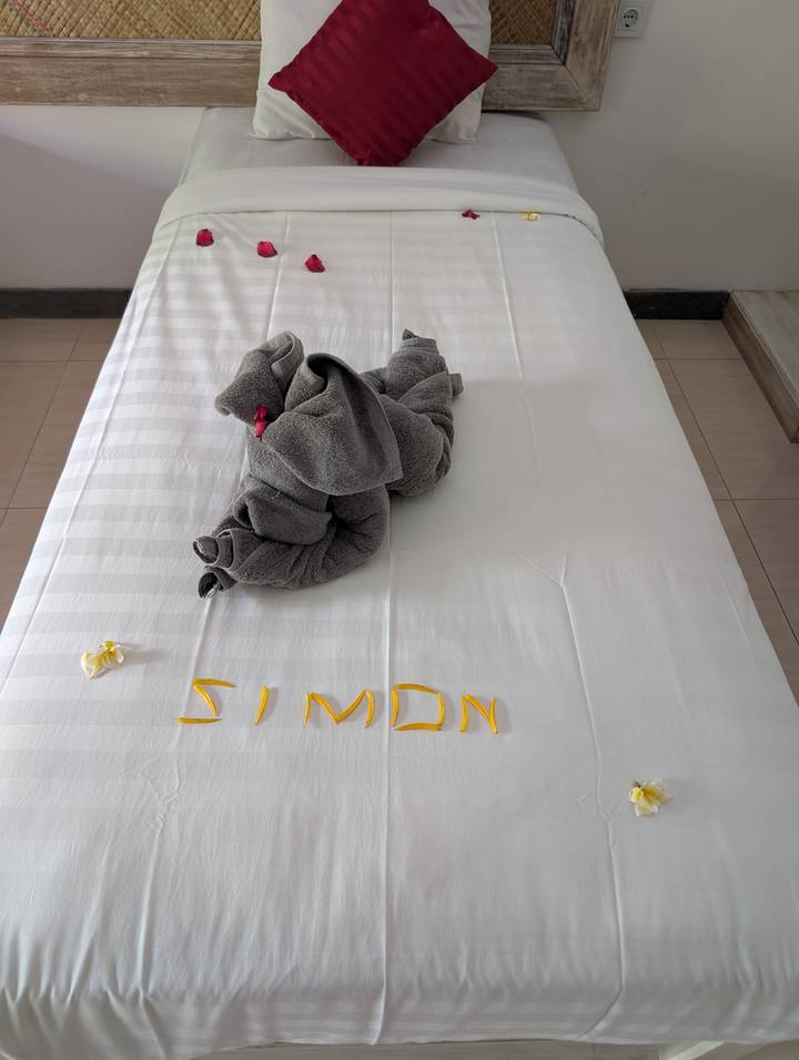 Towel elephant on a bed with 'Simon' spelled out.