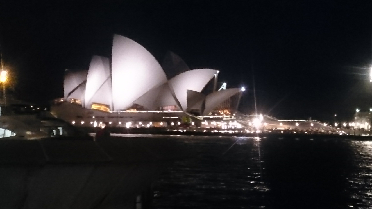 Sydney Opera House at night, illuminated with a reflection in water.