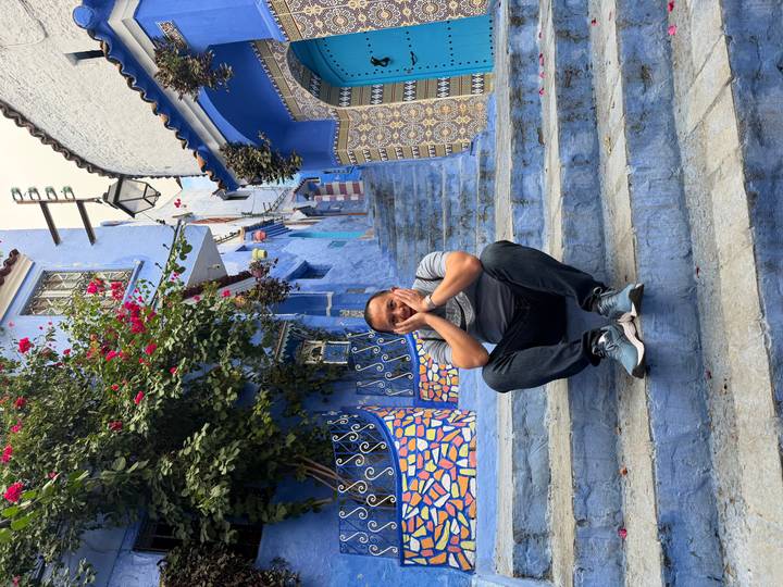Man sitting on colorful steps in a blue-painted alley.