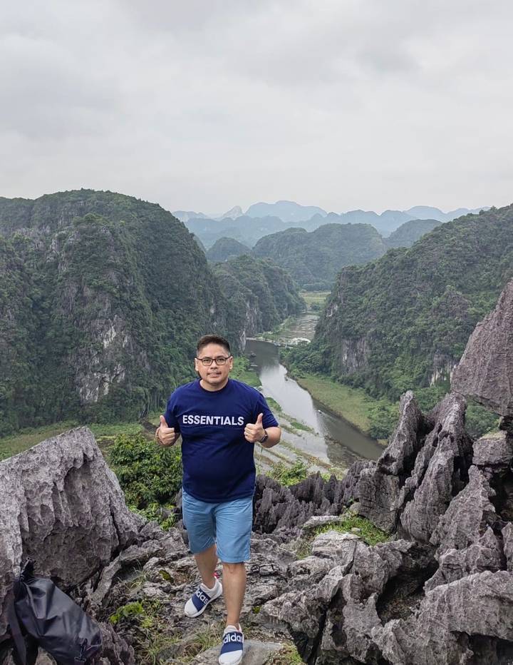 Person standing with a scenic view of karst mountains and a river.