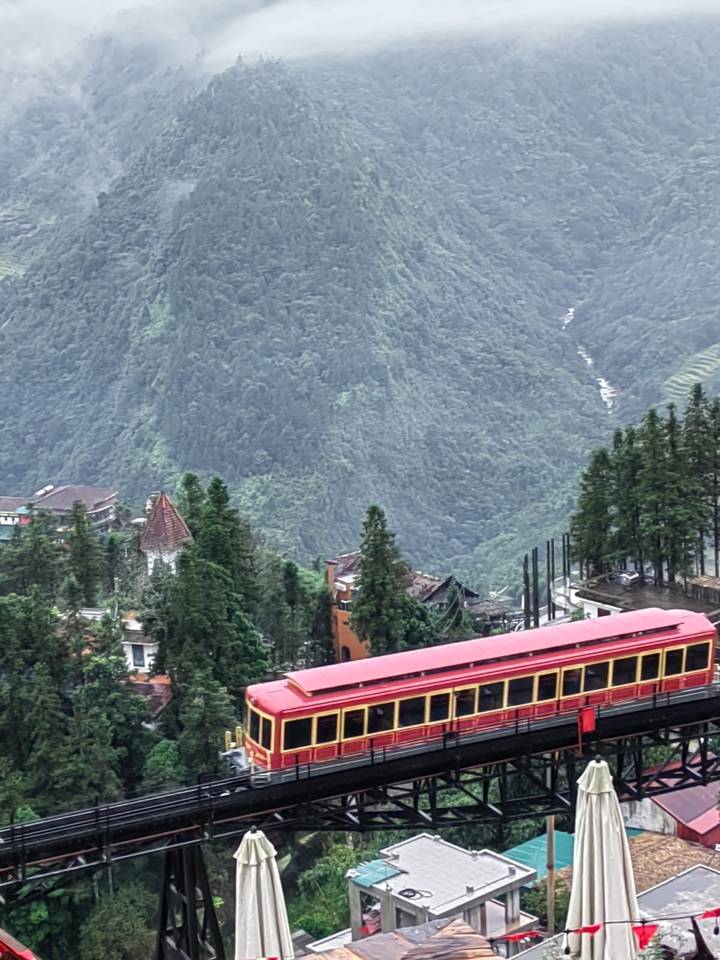 Elevated view of mountains with mist and partially visible buildings.
