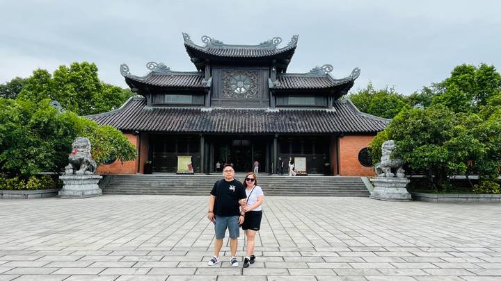 Couple standing in front of a traditional temple building with ornate roof.