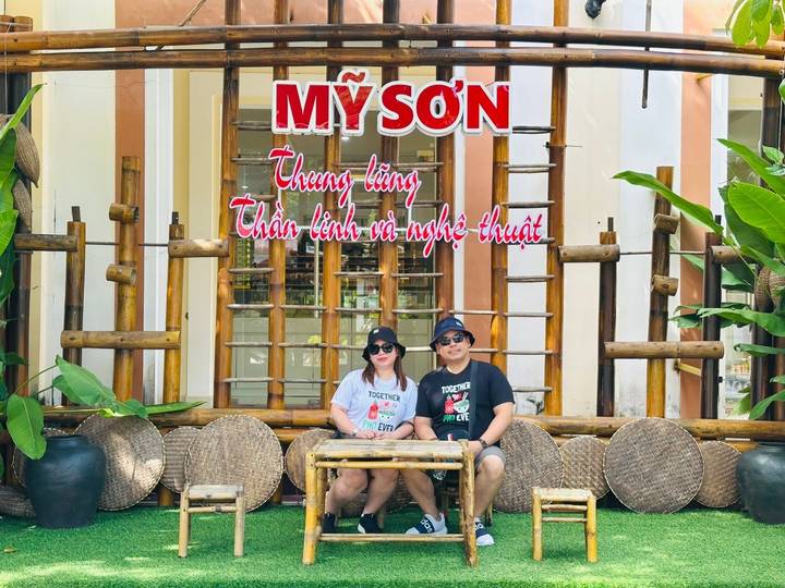 People sitting in front of a colorful sign and bamboo decor.