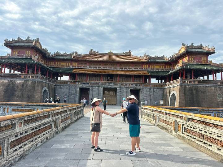 Man and woman holding hands in front of a traditional building with ornate roof.