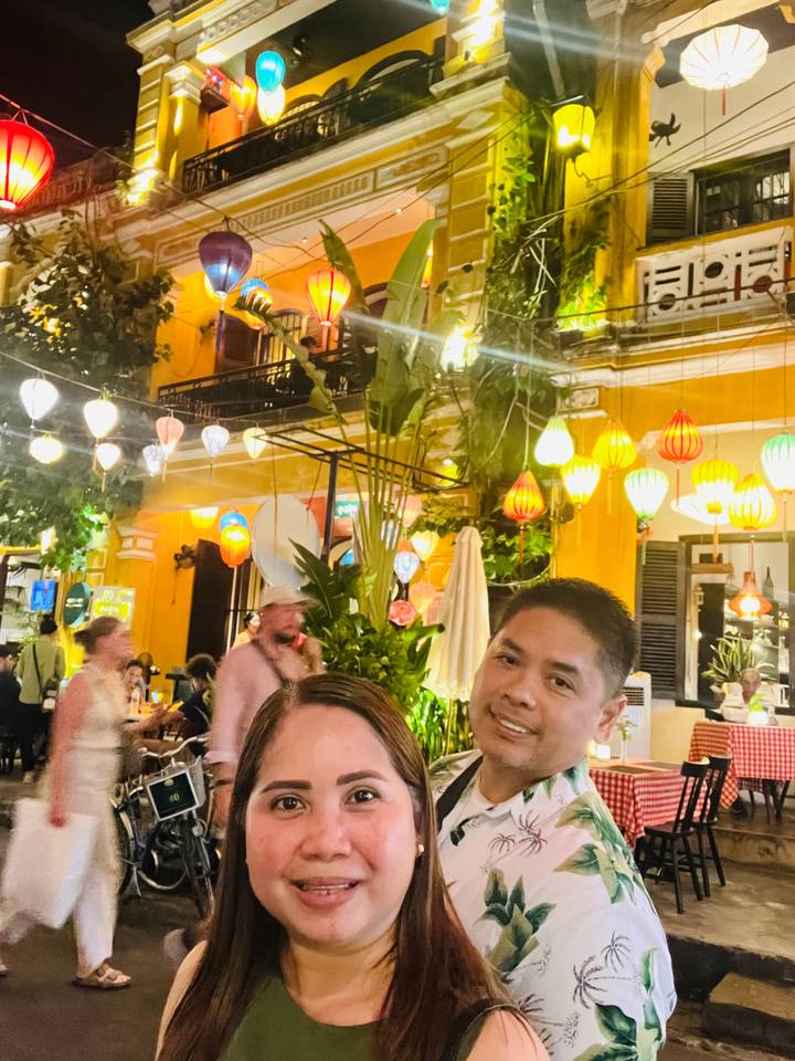 Close-up of a couple in front of a building with colorful lanterns.
