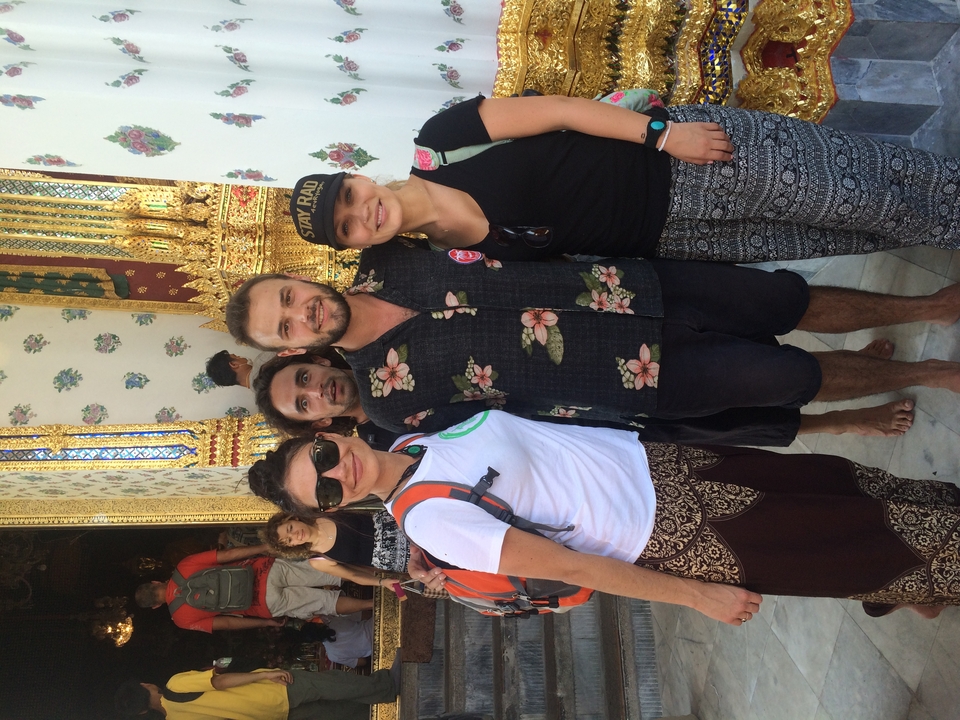 Group of people standing outside near a temple with decorative tiles.