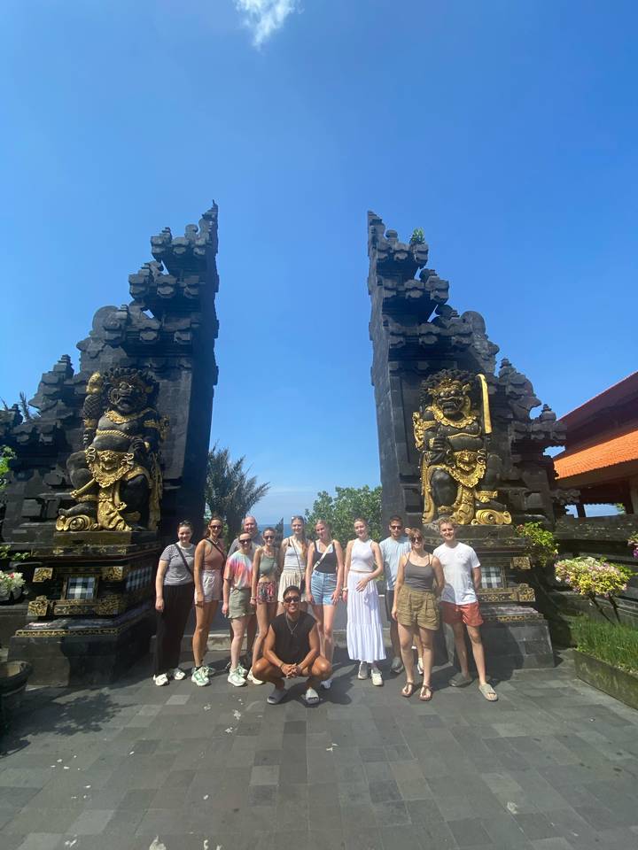 Group of tourists posing in front of traditional Balinese gate statues.