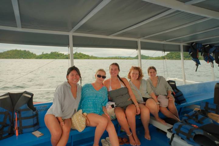 Groep mensen zittend op een boot, met uitzicht op eilanden op de achtergrond.