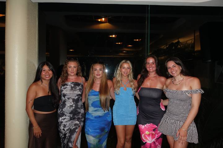 Groep vrouwen die poseren voor een foto binnenshuis 's nachts.