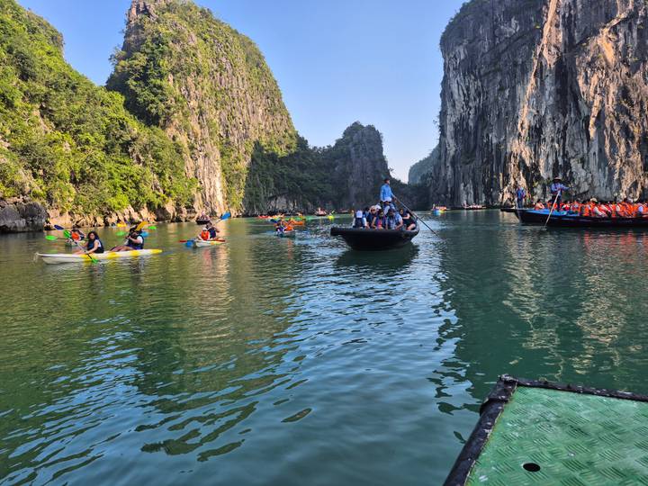 Visitors paddling boats through a picturesque waterway surrounded by cliffs.