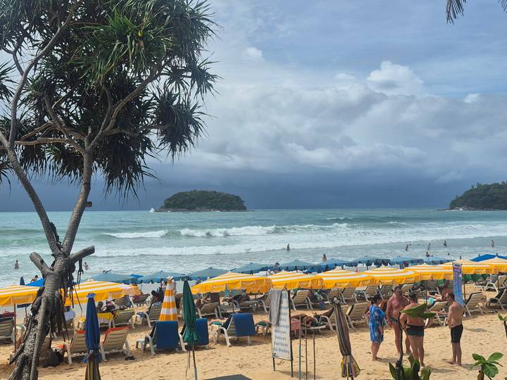 Strand met gele en witte parasols en mensen die genieten van de zee.