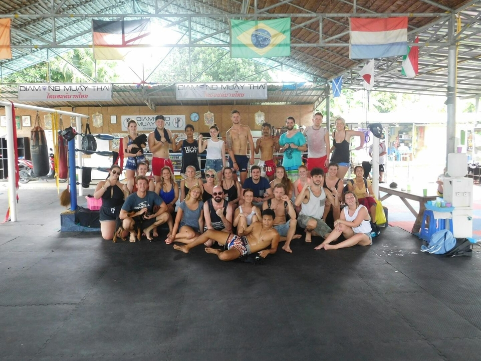 Large group of people posing in a Thai boxing ring.