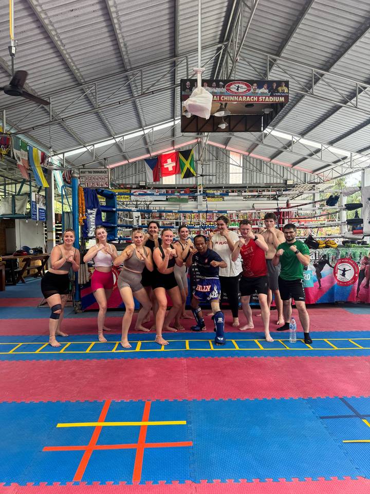 Group posing in a martial arts gym with flags displayed.