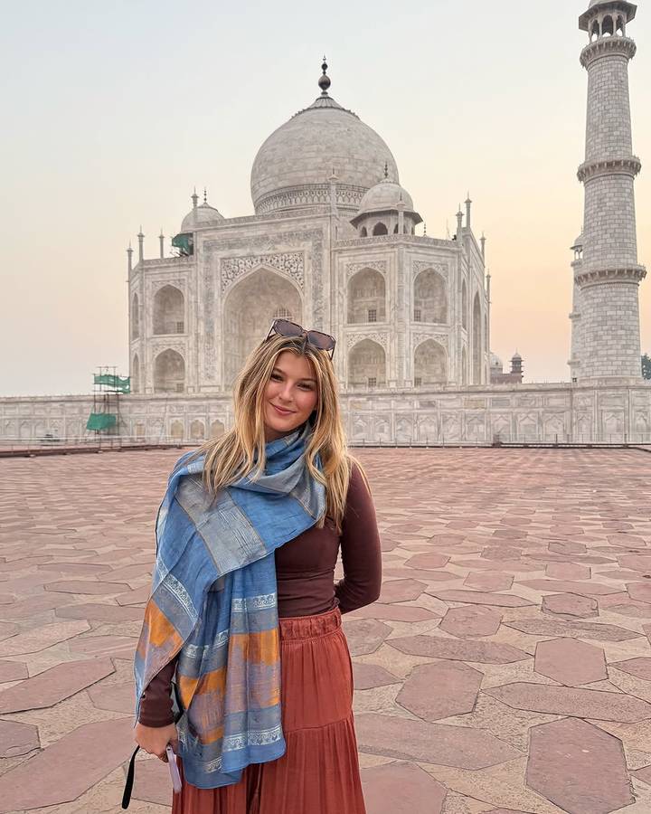 Une femme devant le Taj Mahal, souriante.