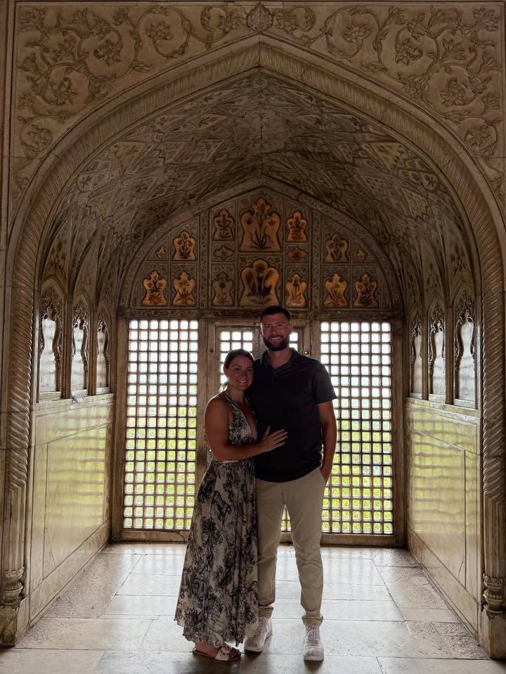 Couple à l'intérieur d'une pièce richement décorée avec des fenêtres à treillis.