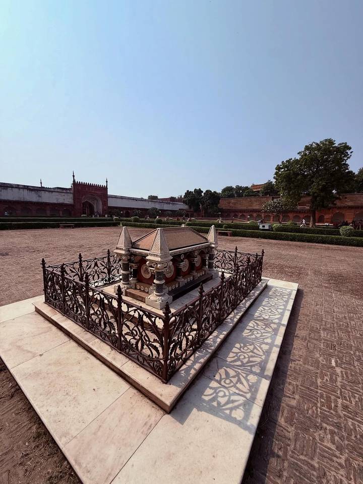 Cour en pierre avec clôture ornée contre un vaste jardin.