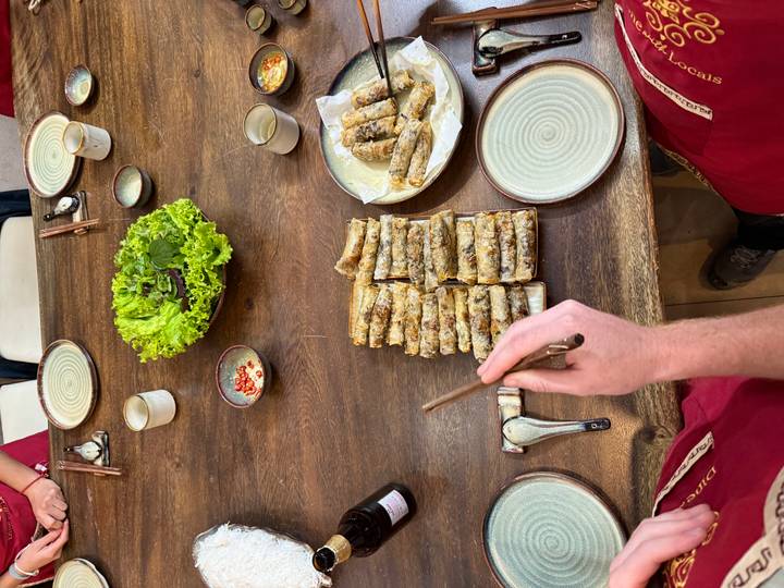 Hand arranging Vietnamese spring rolls on a table.