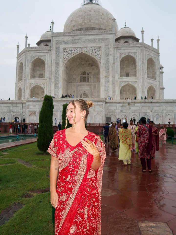 Femme en vêtements traditionnels posant avec le Taj Mahal.