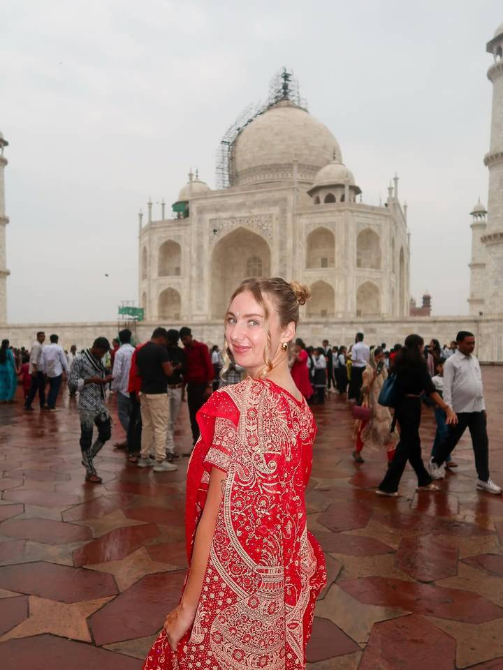 Femme en rouge regardant en arrière avec le Taj Mahal.