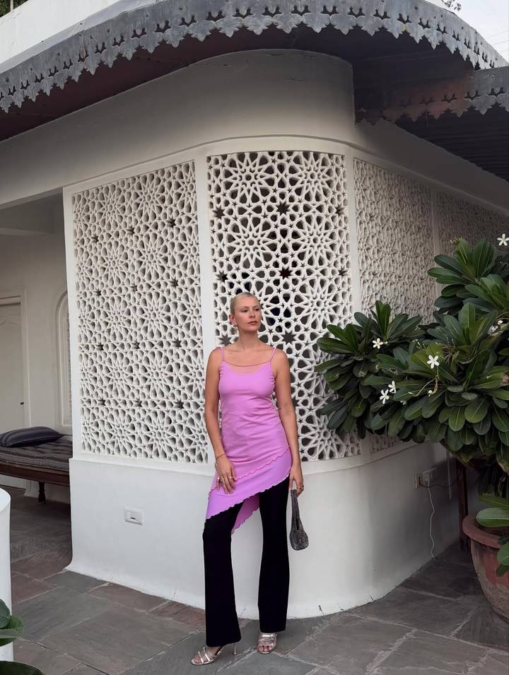 Femme debout près d'un mur au design complexe avec des fleurs.