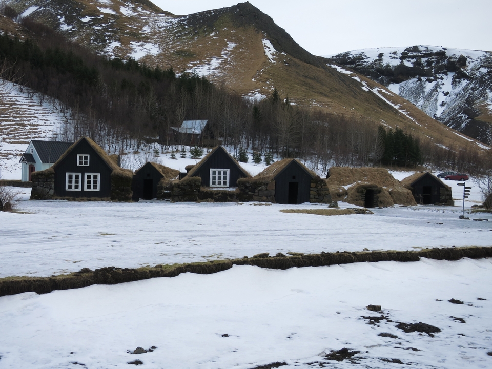 Maisons traditionnelles avec des toits en herbe dans un environnement enneigé.