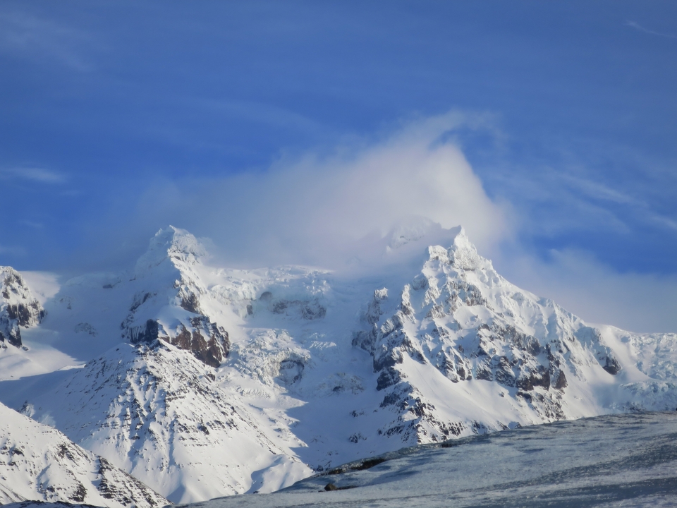 Montagnes enneigées avec des nuages au-dessus.