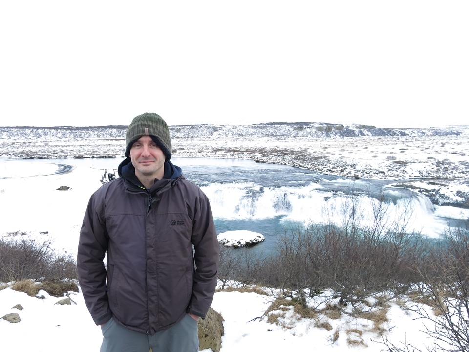 Homme posant devant une cascade gelée.
