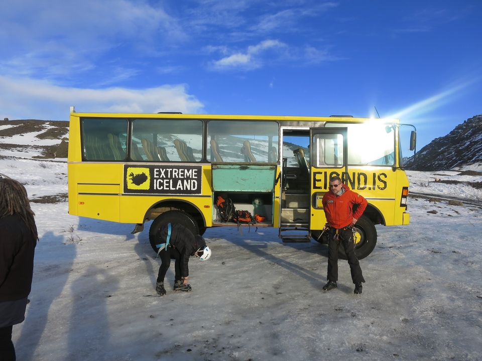 Autobus touristique sur un terrain enneigé avec des personnes.