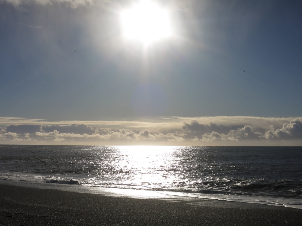 Coucher de soleil sur une mer calme avec une lumière réfléchissante.