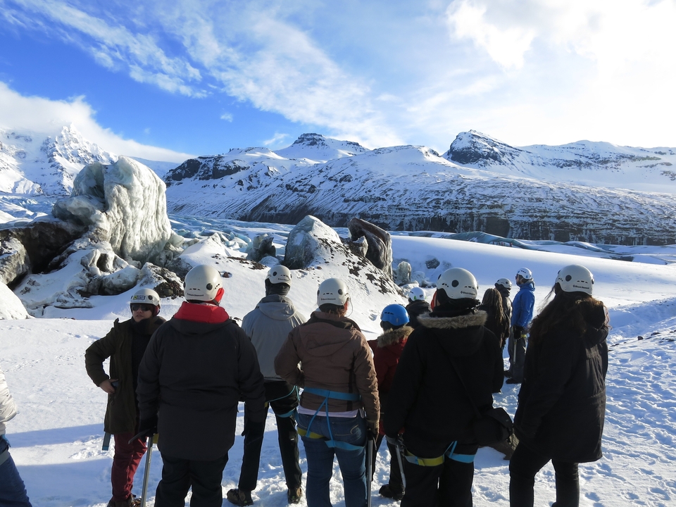 Groupe de personnes casquées explorant un glacier.