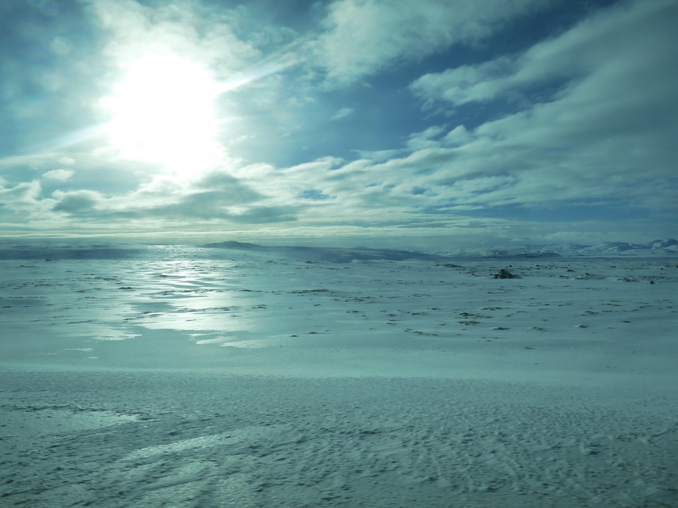 Vaste paysage enneigé sous un ciel lumineux.