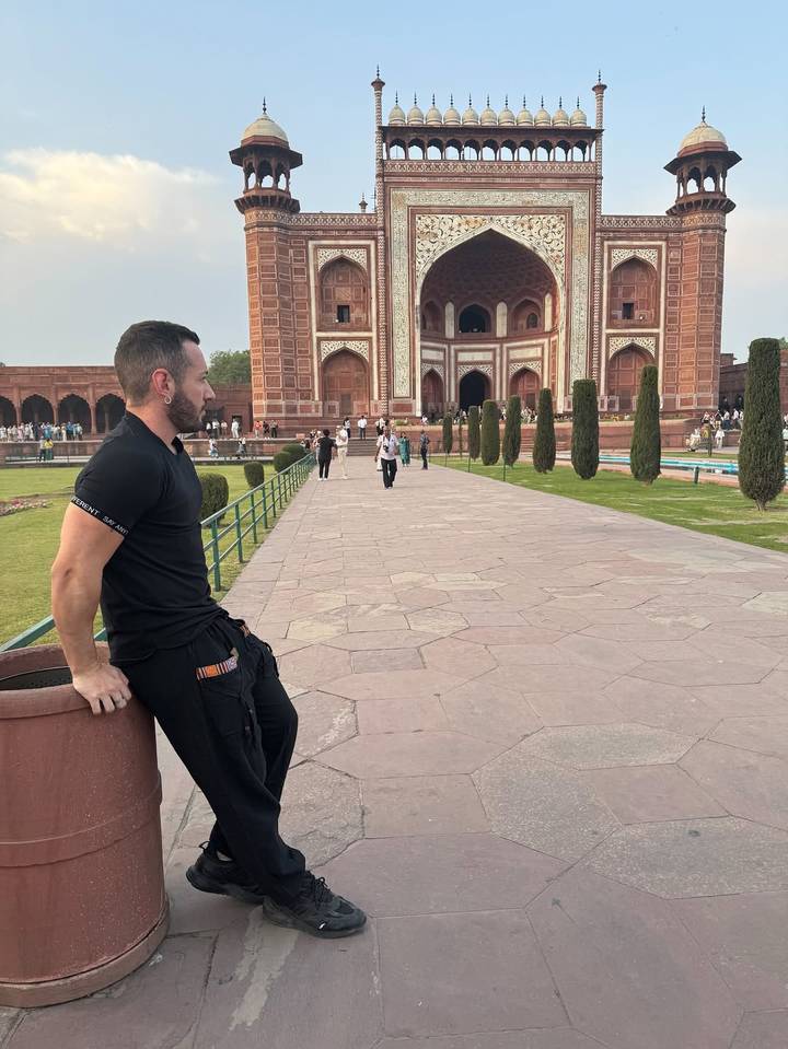 Personne appuyée contre une clôture avec un bâtiment historique en arrière-plan.