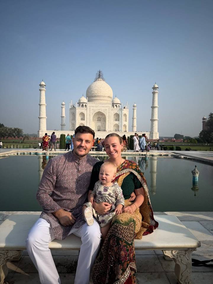 Famille posant devant le Taj Mahal avec bassin de réflexion.