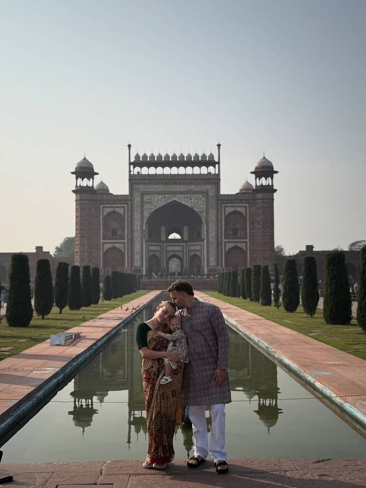 Couple avec un enfant devant une porte monumentale, possiblement la porte du Taj Mahal.