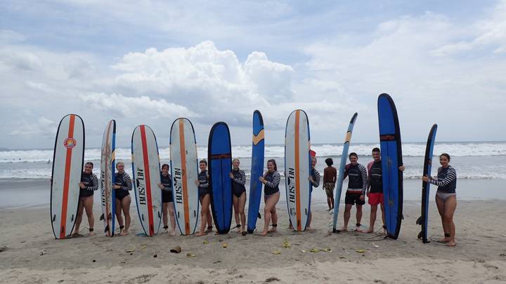 Groep surfers poserend met surfplanken op het strand