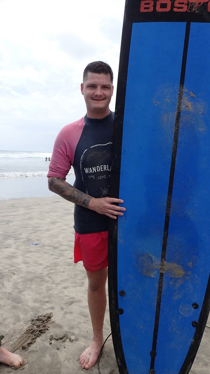 Man poseert met een surfplank op het strand