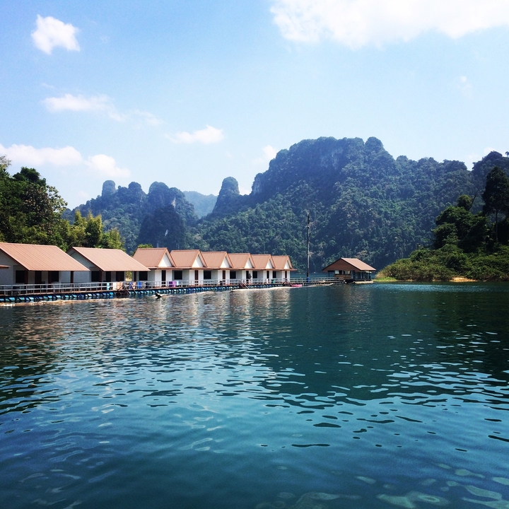 Floating houses on a lake with mountains in the background.