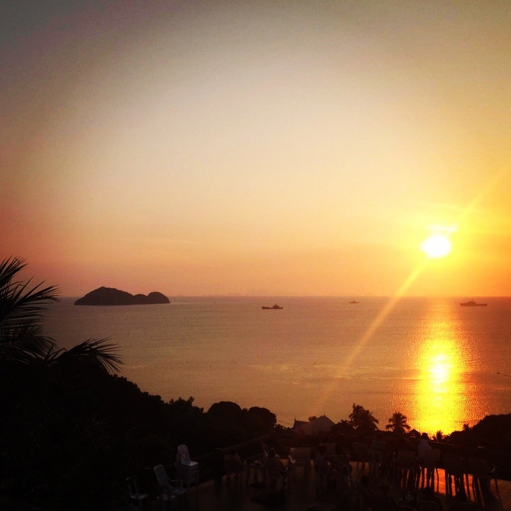 Sunset over the ocean with small islands visible.