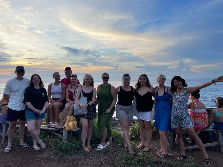 Groep mensen die poseren bij de zee tijdens zonsondergang.