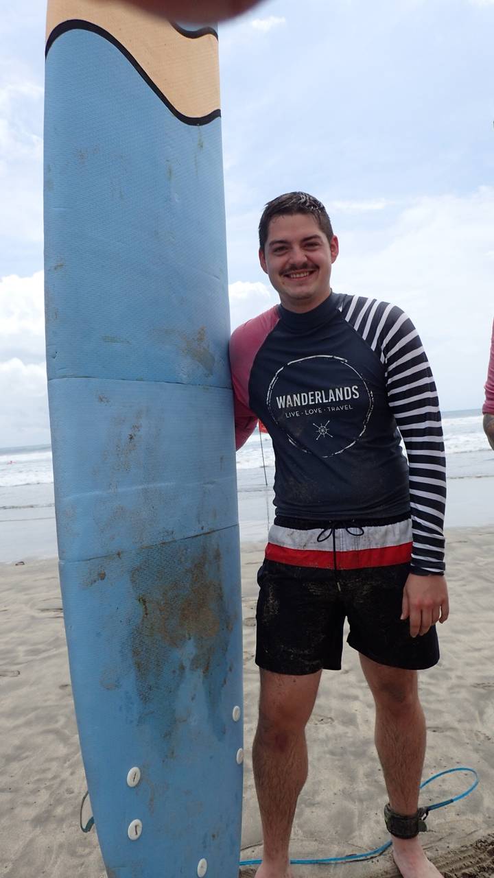 Man met surfplank op strand.