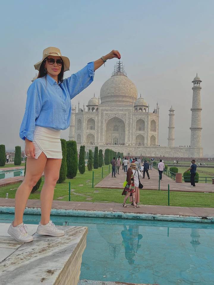 Personne posant avec le Taj Mahal en arrière-plan.