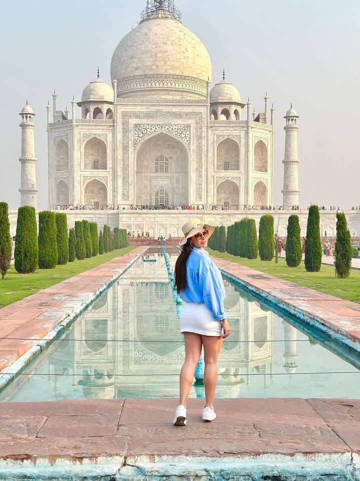 Femme près du bassin de réflexion avec le Taj Mahal en arrière-plan.