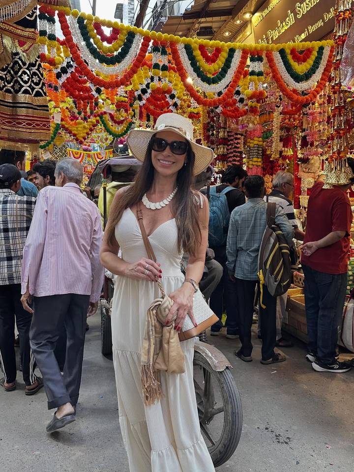 Femme dans un marché animé portant une robe blanche et un chapeau.