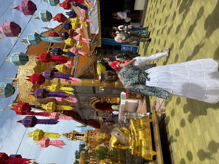 Persoon die naar een tempel loopt met kleurrijke decoraties.