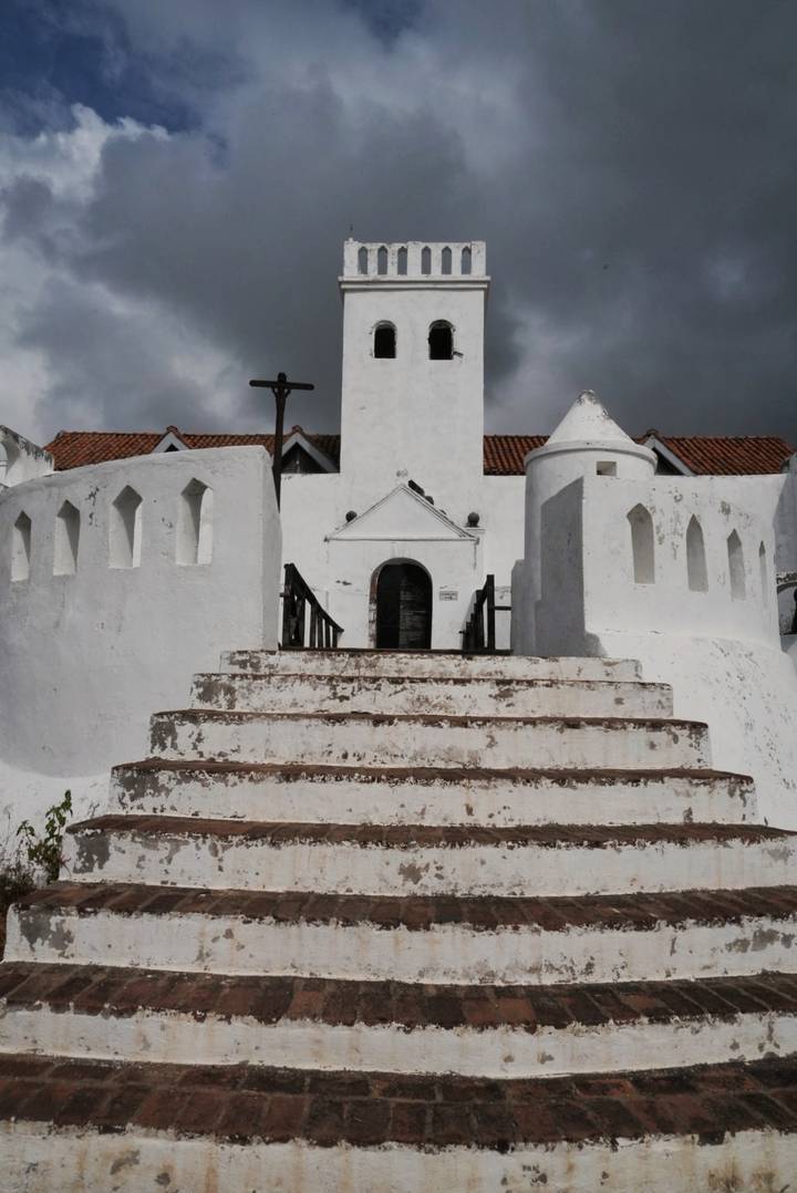 White fort or castle with stairs leading to a large doorway.