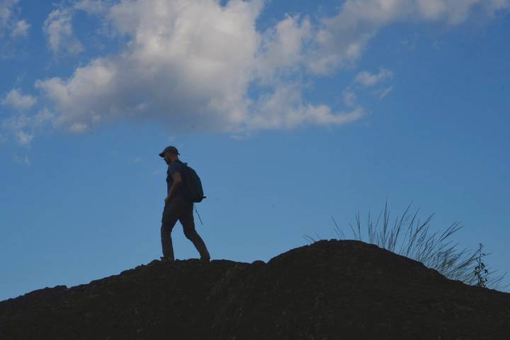 Silhouette of a hiker on a ridge against a blue sky.