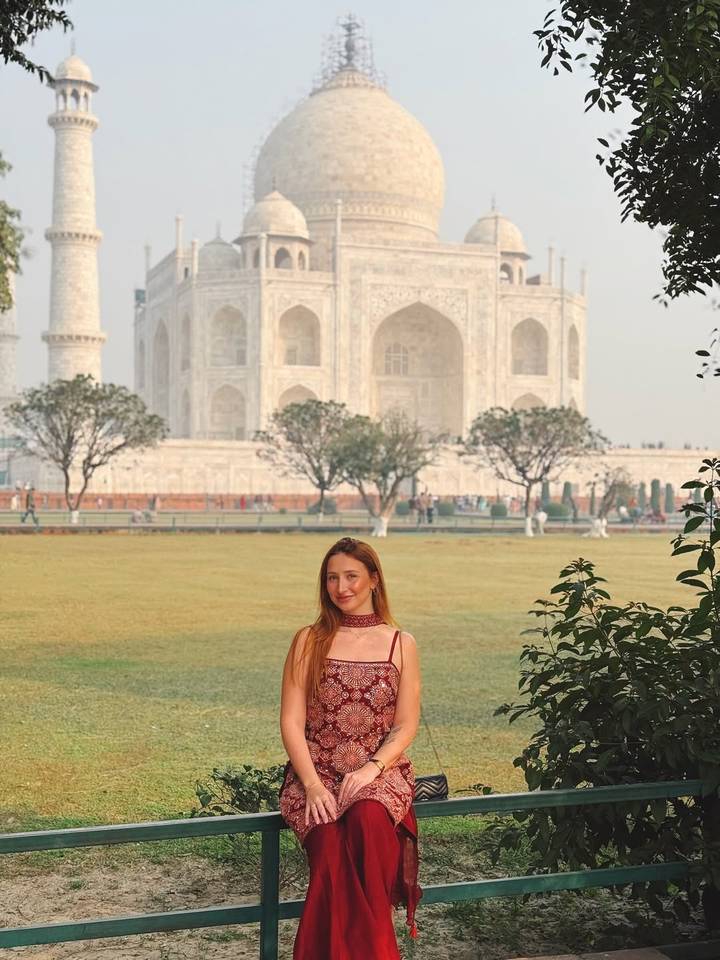 Vrouw poseert met de Taj Mahal op de achtergrond.